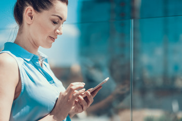 Poster - Side view smiling girl working with mobile during walkoutdoor. She looking at screen of appliance. Copy space