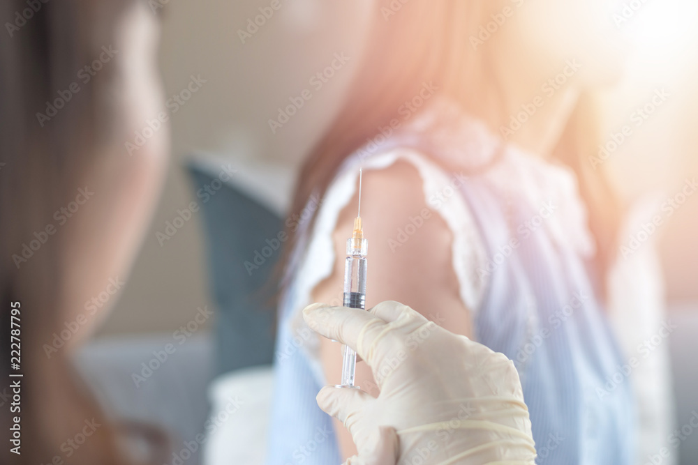 World immunization week and International HPV awareness day concept. Woman having vaccination for influenza or flu shot or HPV prevention with syringe by nurse or medical officer. - obrazy, fototapety, plakaty 