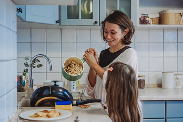 A little cute girl and her mother in the kitchen at home