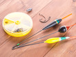 Fishing accessories - floats, hooks, round yellow boxes, on a wooden background