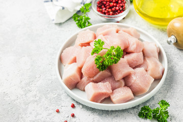 Raw meat cubes in a bowl with parsley, seasonings and olive oil. Selective focus, space for text.