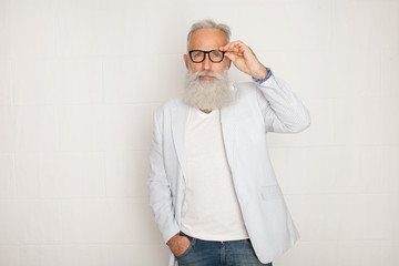 Wall Mural - Cheerful happy mature man in glasses looking camera and smiling over white wall