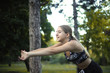 © Sunrise Team - Happy cheerful young teenage girl woman outdoors in a park looking aside make stretching exercises.