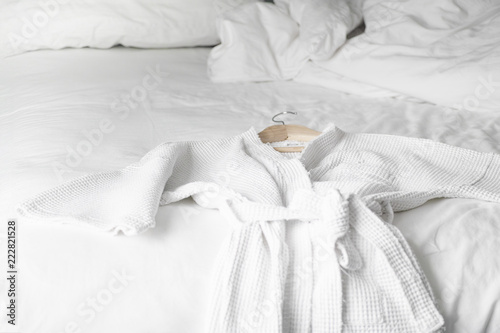 Fotografía white bath robe on the bed in hotel room