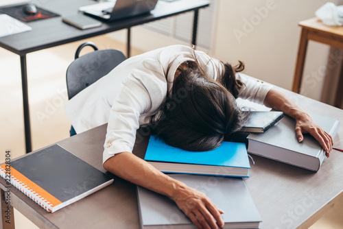 Tired Female Student Sleeping On Desk Face And Hands On Books