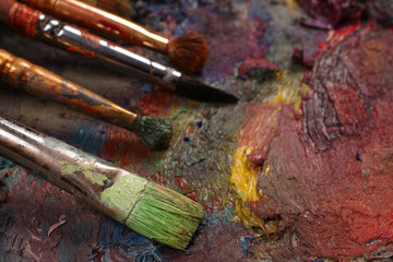 Paintbrushes closeup, artist palette and multicolor paint stains