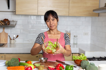 Healthy food Asian woman is cooking salad in kitchen, female preparing the vegetables and fruit at her house