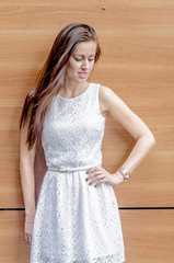 Wall Mural - Young girl in a white dress near a wooden wall
