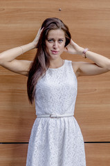 Wall Mural - Young girl in a white dress near a wooden wall
