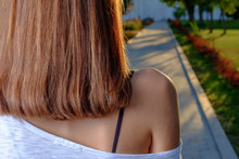 Back View Of The Young Female With Red Beautiful Straight Long Hairs Posing With Bare Shoulder Looking At Alley