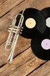 Trumpet and vinyl records on wooden boards. Vinyl plates and trumpet on rustic wooden floor, top view.