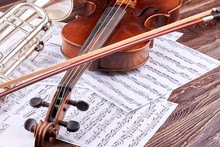 Close Up Violin, Bow And Musical Notes. Vintage Violin, Trumpet And Music Sheets On Wooden Background. Classical Music Instruments Background.