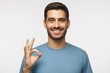 Young smiling man having happy look, gesturing, showing OK sign or showing okay gesture with his fingers