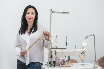 Young woman in fashion atelier working with measuring tape