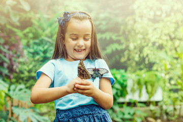 Wall Mural - Little girl is playing with butterfly in nature