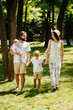 © Leika production - Beautiful woman wears the white clothes and hat walks with handsome father and children in the wonderful park on a summer day.