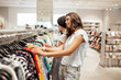 © Leika production - Two good looking smiling slim girls with long dark hair,wearing casual style,have shopping in a modern mall.