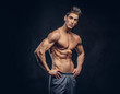 © Fxquadro - Handsome shirtless ectomorph bodybuilder with stylish hair posing on a dark background.