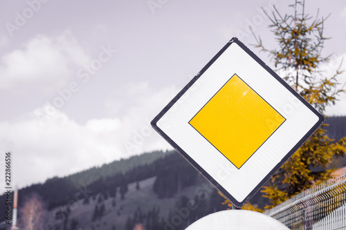 Blank Yellow Road Sign Meaning Yield Pedestrians And Main High Priority Road On Sky Background In Nature Forest Mountains Safety Concept In Rural Ambience Out Of Town Buy This