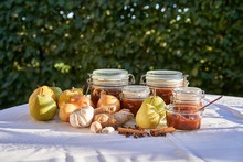 Cooking And Preserving Pear Chutney, All Ingredients And Cooked Chutney In Kilner Jars, Pears, Garlic, Fresh Ginger, Onion, Cinnamon And Clove On Table In The Garden