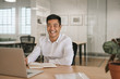 © mavoimages - Smiling young Asian businessman working at his office desk