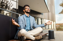 Businessman - Mentally Preparing For Business Meeting. Sitting In Meditation Pose In Front Of Office Building And Smiling  