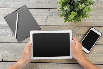 Sticker - hands of a man holding tablet device over a wooden workspace table