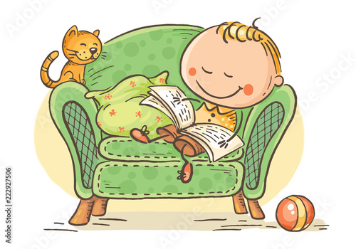 Little child reading a book in an arm-chair with his cat