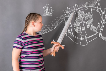 The girl is developing a plan for taking the medieval fortress, pointing with the sword at the weak points in the defense on the drawn plan