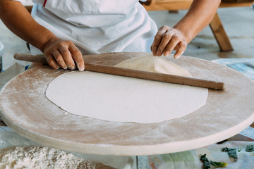 Woman rolls out dough, Turkish traditional flat cakes.