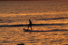 Two men doing Jetsurf or motor surf at sunset : orange and golden light in the sea