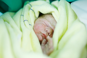 Newborn baby child seconds and minutes after birth wrapped in towel