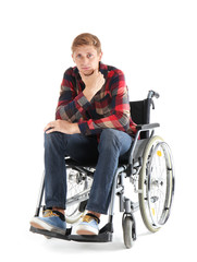 Thoughtful young man sitting in wheelchair on white background