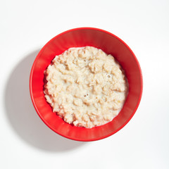 Oatmeal Porridge with Milk in Red Bowl Isolated on White Background