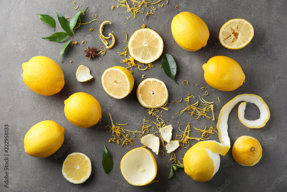 Composition with ripe lemons and fresh zest on grey background