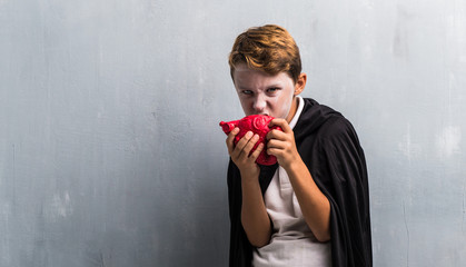 Wall Mural - Boy in vampire costume for halloween holidayse eating a heart