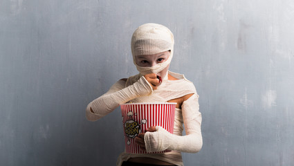 Wall Mural - Boy in mummy costume eating popcorns for halloween holidays