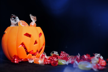 halloween Jack o Lantern candy collector full of candy and some scattered sweets on the black background