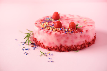 Delicious raspberry cake with fresh berries, rosemary and dry flowers on pink background. Copy space for your text. Vegetarian, vegan food concept