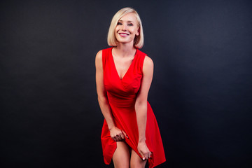 Sexy young beauty blonde woman in red dress in studio on a black background