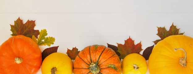 Yellow and orange pumpkins and autumn leaves on white wooden background for harvest fall and thanksgiving theme.