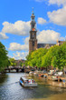 Canalboat tour at the UNESCO world heritage Prinsengracht canal with the Westerkerk (Western church) on a sunny summer day with blue sky and clouds