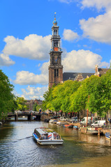 Wall Mural - Canalboat tour at the UNESCO world heritage Prinsengracht canal with the Westerkerk (Western church) on a sunny summer day with blue sky and clouds