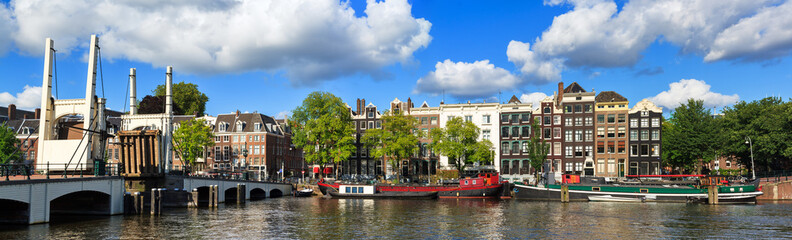 Wall Mural - Beautiful panoramic panorama of the skinny bridge (magere brug) while open over the river Amstel in Amsterdam, the Netherlands, on a sunny summer day with some clouds