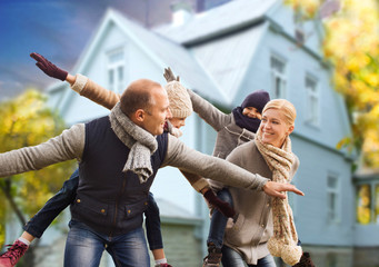 Canvas Print - family, real estate and people concept - happy mother, father, daughter and son having fun over living house background outdoors in autumn