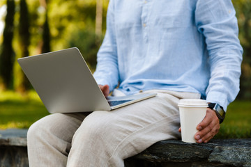 Wall Mural - Close up of a man working on laptop while sitting at the park