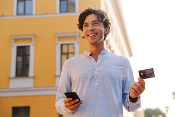 cheerful young casual man holding mobile phone