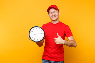 Wall Mural - Delivery man in red uniform isolated on yellow orange background. Professional smiling male employee in cap, empty t-shirt working as courier or dealer holding round clock. Service concept. Copy space