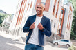© Friends Stock - Outdoors leisure. Young man walking on the city street touching jacket looking forward smiling cheerful