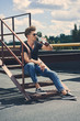 © LIGHTFIELD STUDIOS - stylish man drinking rum while sitting on stairs on roof